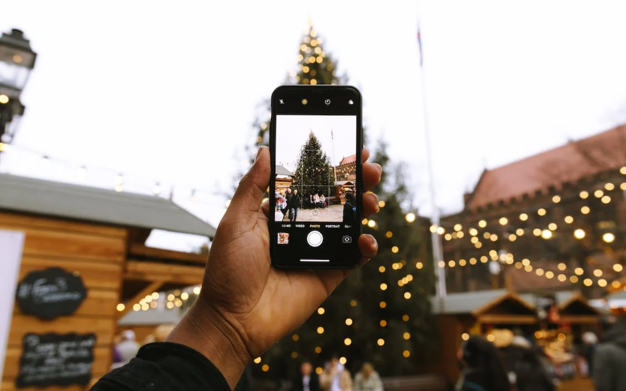 Persona che fa foto con lo smartphone ad albero di Natale mercatini di Natale